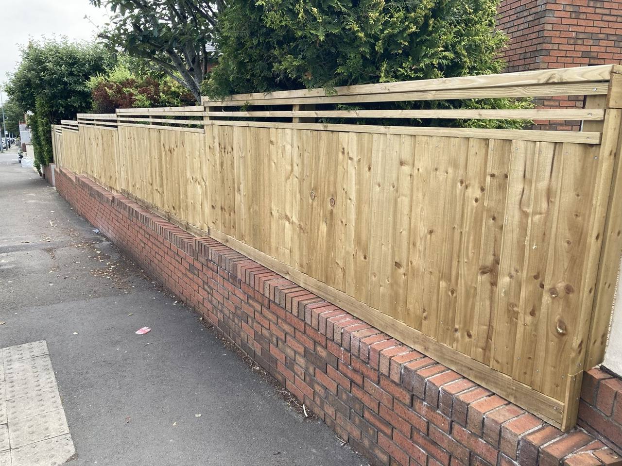 Featheredge fence with a slatted top stepping down to follow a sloping front wall