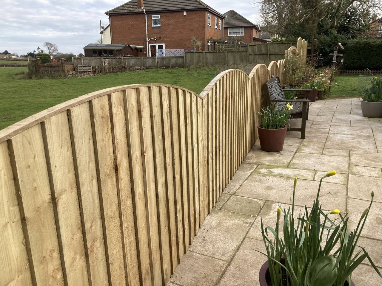 Curved-top fence panels following a patio